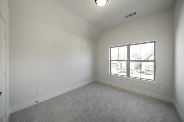 spare room with light carpet, baseboards, visible vents, and lofted ceiling