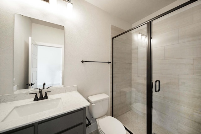 full bath with vanity, a shower stall, and toilet