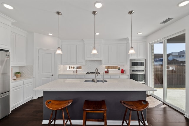 kitchen featuring visible vents, dark wood-style flooring, a sink, stainless steel appliances, and white cabinets