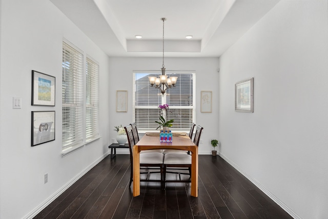 dining space featuring a tray ceiling, a notable chandelier, wood finished floors, and baseboards