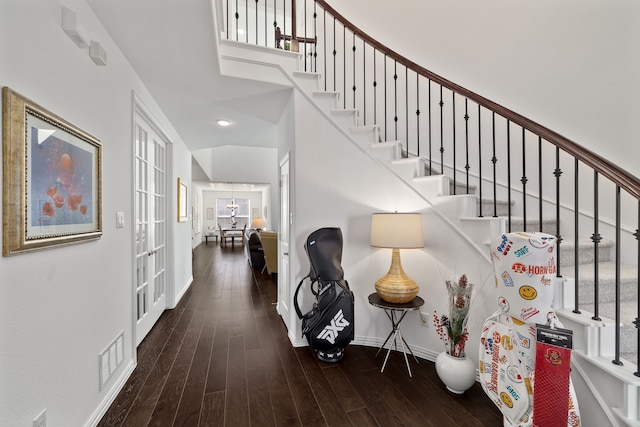 interior space featuring visible vents, baseboards, stairs, a high ceiling, and wood finished floors