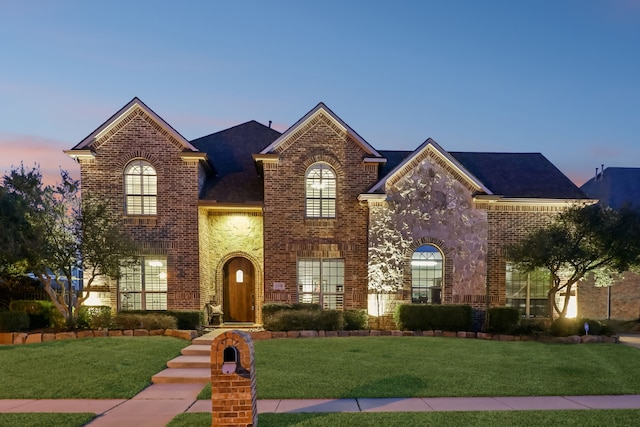 view of front of home with a yard, stone siding, and brick siding