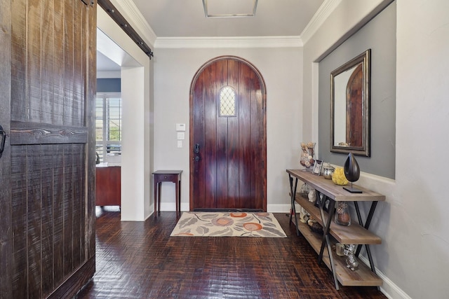 foyer entrance with brick floor, arched walkways, crown molding, a barn door, and baseboards