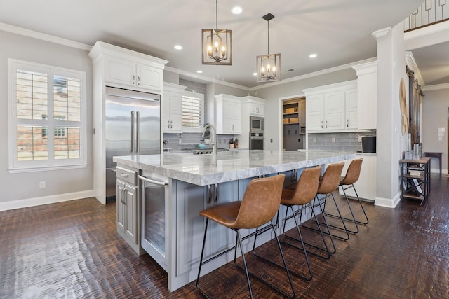 kitchen with built in appliances, ornamental molding, white cabinets, and baseboards