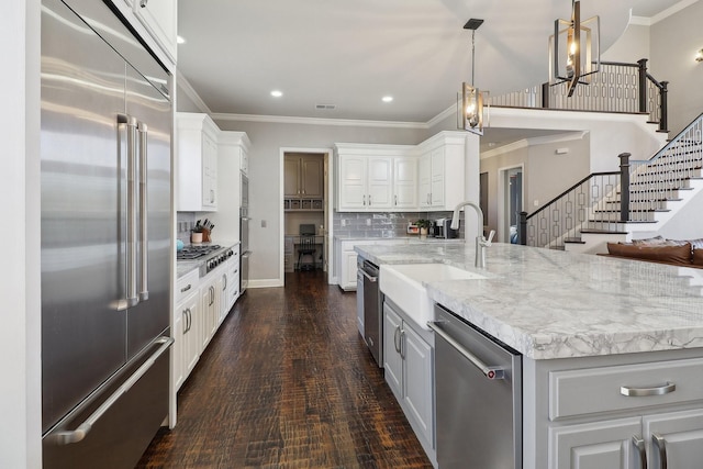 kitchen with white cabinetry, ornamental molding, stainless steel appliances, and backsplash