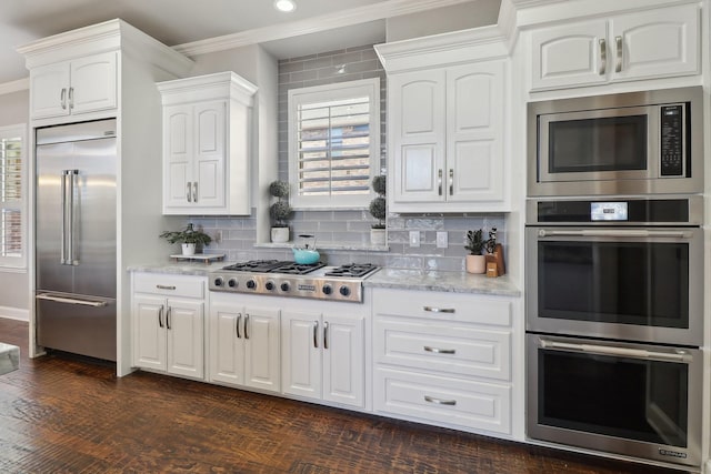 kitchen featuring white cabinetry, decorative backsplash, dark wood-style flooring, and built in appliances