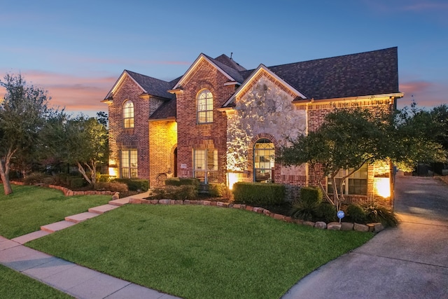 view of front of house with stone siding, brick siding, and a yard