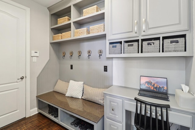 mudroom with baseboards, dark wood finished floors, and built in desk