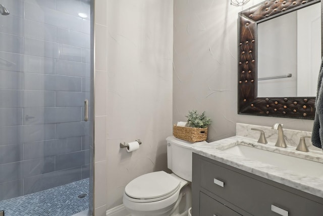 bathroom with toilet, tiled shower, and vanity