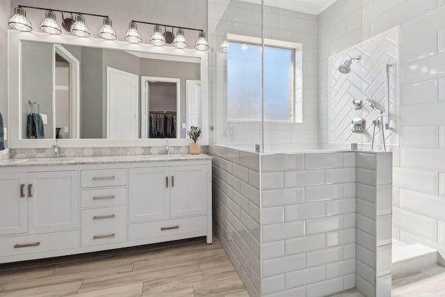 bathroom featuring a walk in shower, double vanity, wood finished floors, and a sink