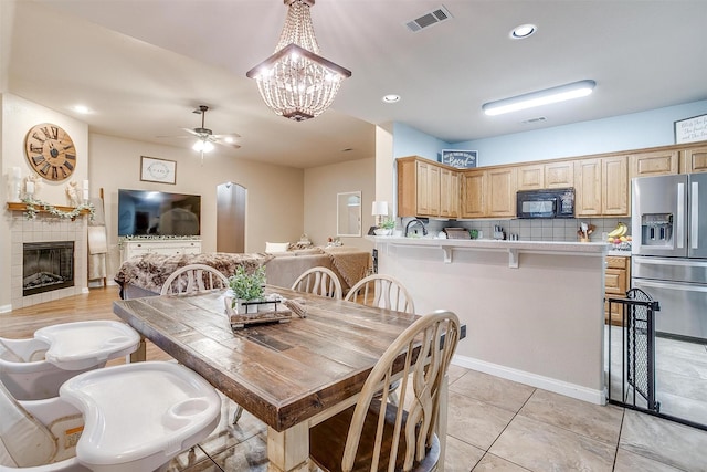 dining room with recessed lighting, visible vents, a tiled fireplace, and ceiling fan with notable chandelier