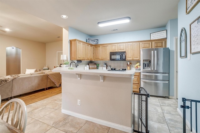 kitchen featuring tasteful backsplash, light countertops, visible vents, appliances with stainless steel finishes, and a kitchen breakfast bar