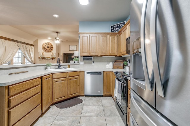 kitchen featuring a peninsula, a sink, light countertops, black appliances, and tasteful backsplash