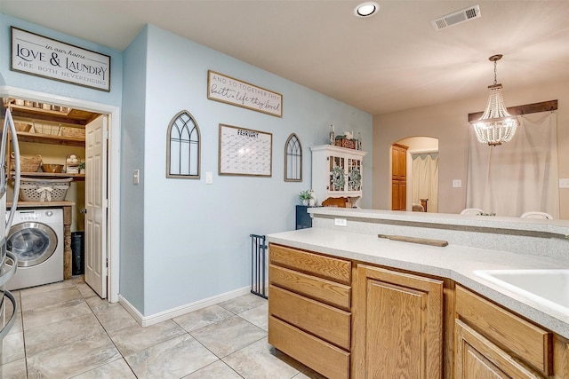 kitchen featuring visible vents, arched walkways, washer / clothes dryer, hanging light fixtures, and light countertops