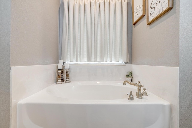 bathroom with a textured wall and a bath