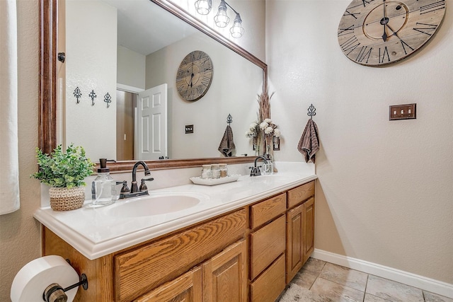 bathroom with double vanity, tile patterned flooring, baseboards, and a sink