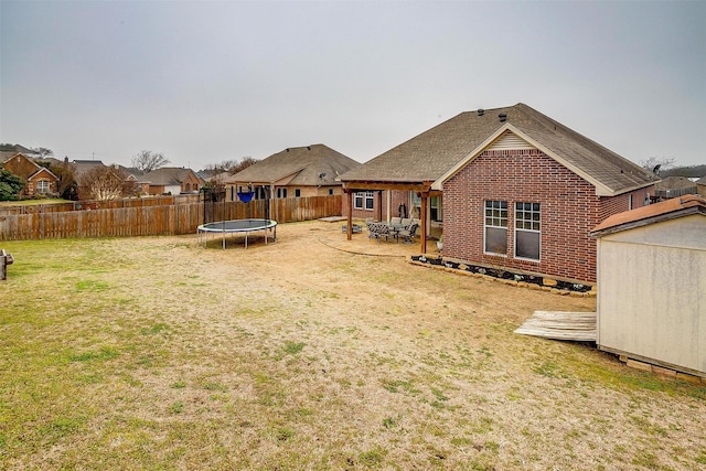 view of yard featuring a trampoline, an outbuilding, a patio, a storage shed, and a fenced backyard