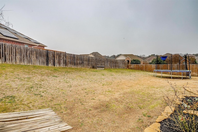 view of yard with a trampoline and a fenced backyard