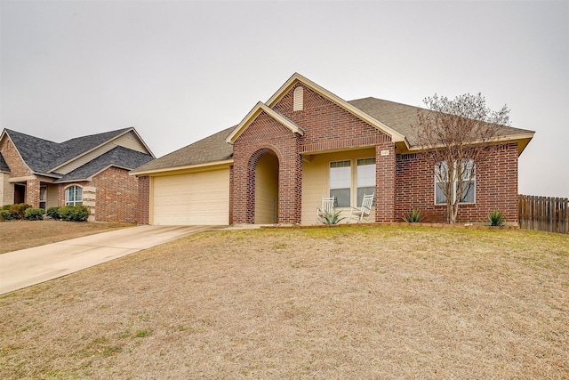 view of front of property with a garage, brick siding, fence, driveway, and a front lawn