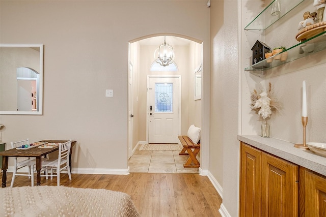 entryway featuring arched walkways, baseboards, and light wood finished floors