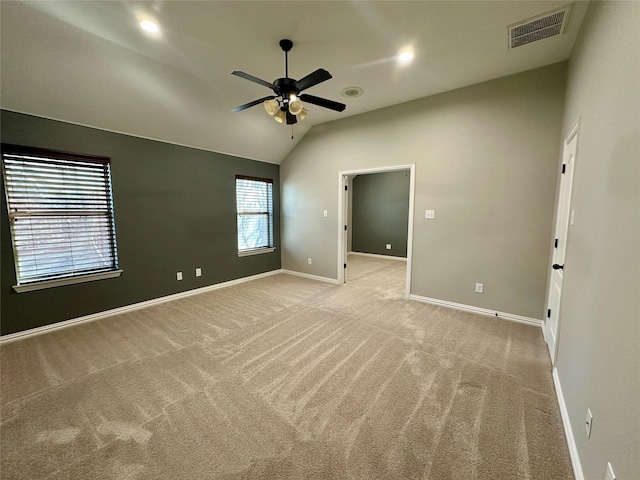 unfurnished bedroom with visible vents, a ceiling fan, light carpet, vaulted ceiling, and baseboards