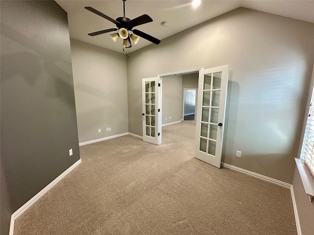 carpeted spare room with ceiling fan, baseboards, vaulted ceiling, and french doors