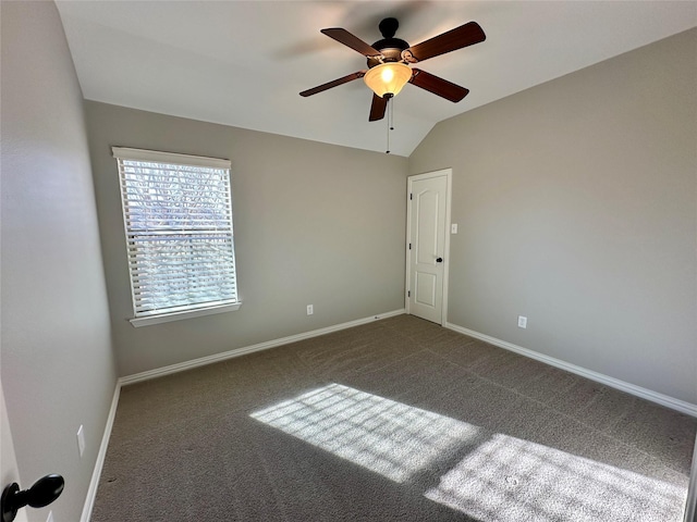 unfurnished room with dark colored carpet, vaulted ceiling, baseboards, and ceiling fan