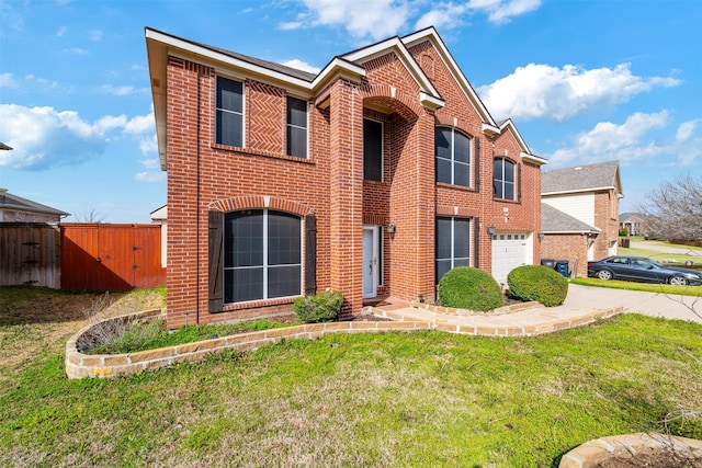 traditional-style home featuring concrete driveway, an attached garage, fence, a front lawn, and brick siding