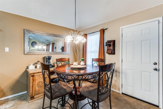 dining room with concrete flooring, baseboards, and an inviting chandelier