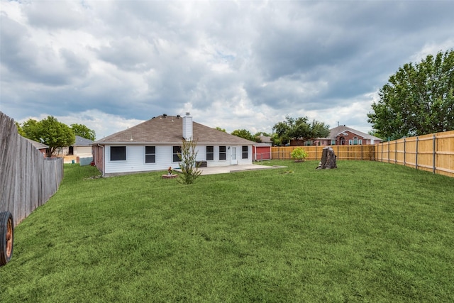 back of house with a fenced backyard, a patio, a chimney, and a lawn