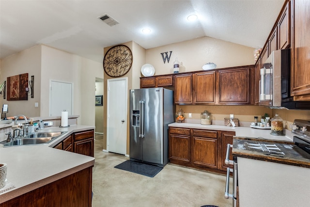 kitchen featuring lofted ceiling, stainless steel appliances, a sink, visible vents, and finished concrete flooring