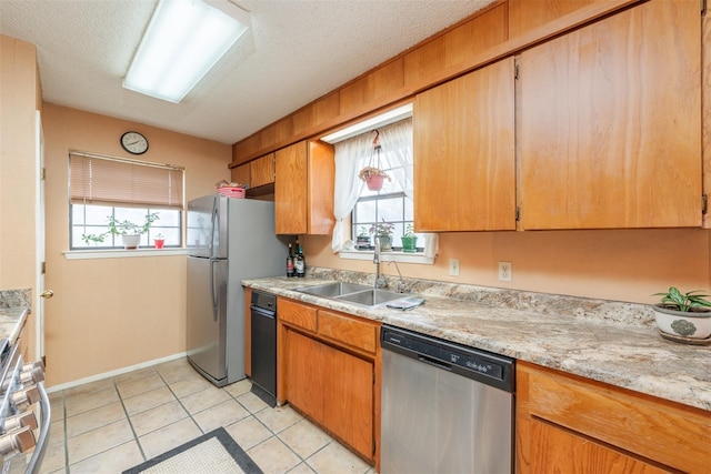 kitchen with light tile patterned floors, stainless steel appliances, light countertops, a sink, and a textured ceiling