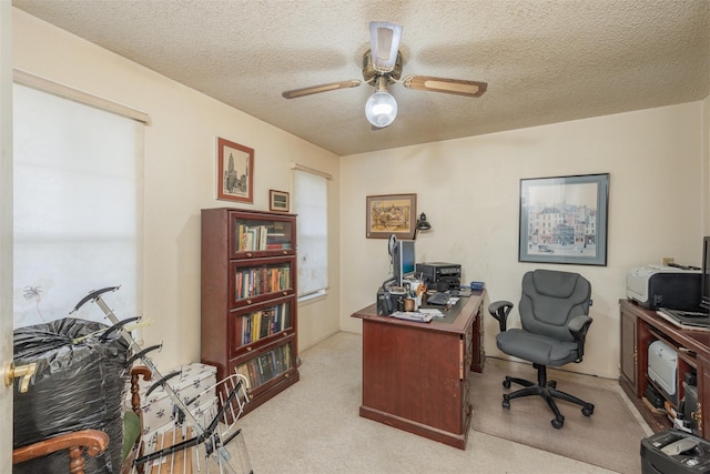 carpeted office space featuring ceiling fan and a textured ceiling