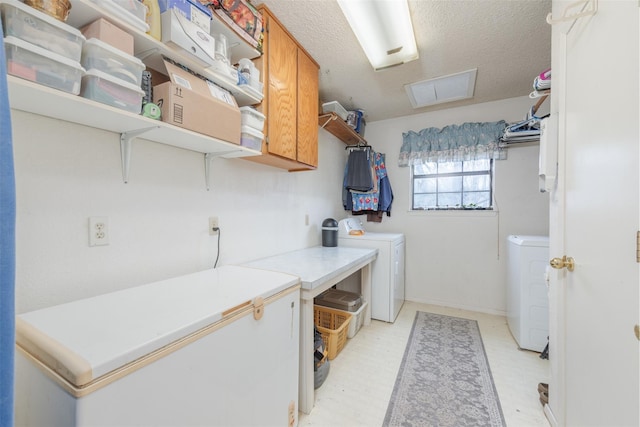 laundry room featuring cabinet space, independent washer and dryer, a textured ceiling, and light floors