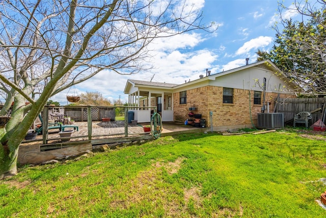 back of house featuring fence, a deck, cooling unit, a yard, and brick siding