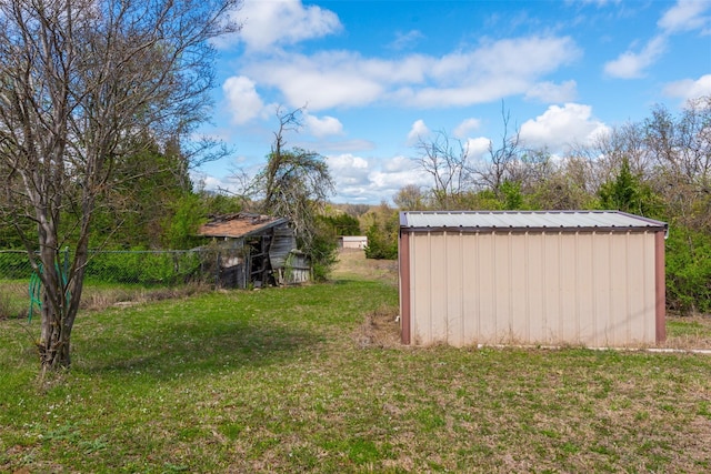 view of yard featuring an outdoor structure, fence, and a shed