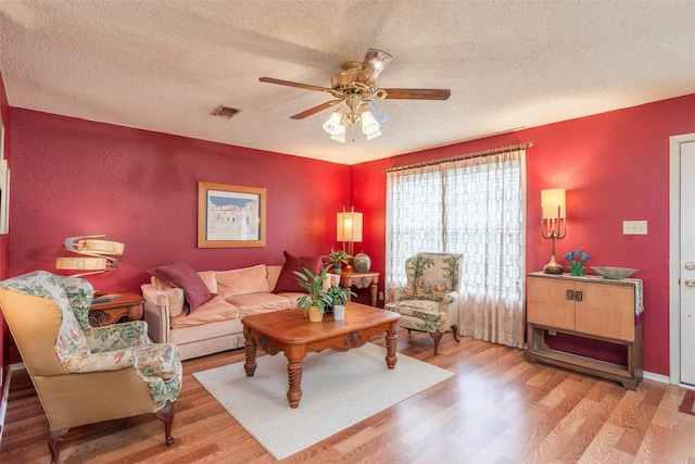 living area featuring visible vents, ceiling fan, a textured ceiling, and wood finished floors