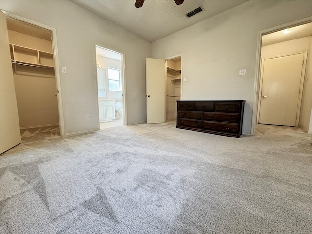 unfurnished bedroom with a closet, visible vents, a spacious closet, and carpet flooring