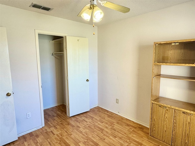 unfurnished bedroom featuring a closet, visible vents, light wood-style flooring, a textured ceiling, and baseboards