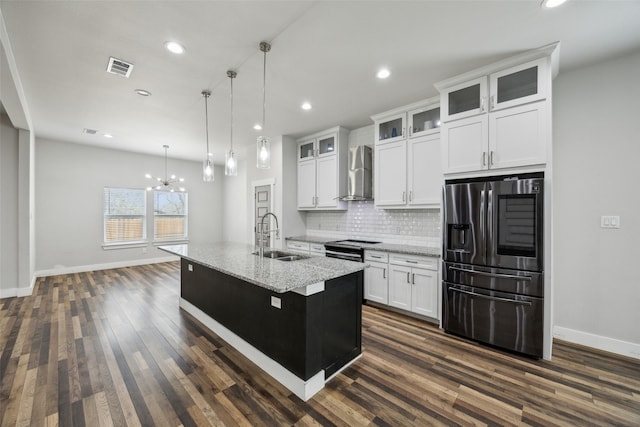 kitchen featuring a sink, tasteful backsplash, white cabinetry, stainless steel appliances, and wall chimney range hood