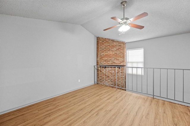 empty room featuring vaulted ceiling, ceiling fan, a textured ceiling, and wood finished floors