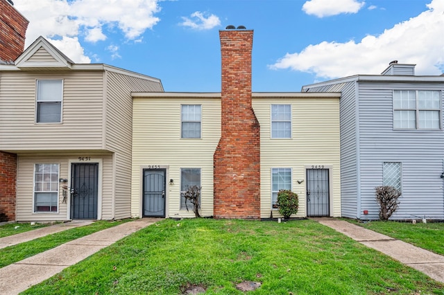 multi unit property featuring a chimney and a front yard