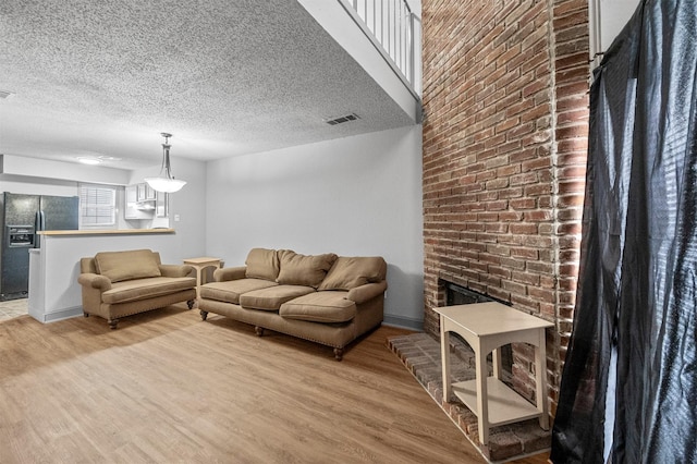 living room with baseboards, visible vents, light wood-style flooring, and a textured ceiling