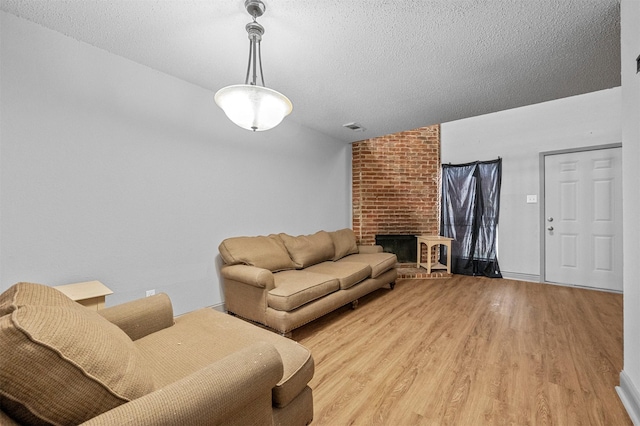 living room with a textured ceiling, vaulted ceiling, a fireplace, and light wood-style floors