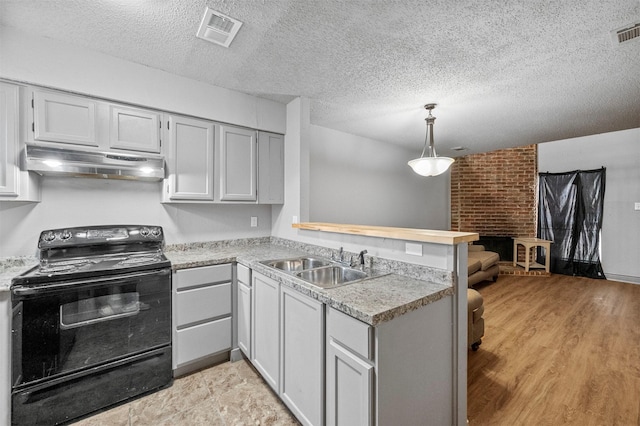 kitchen featuring visible vents, a sink, a peninsula, under cabinet range hood, and black / electric stove