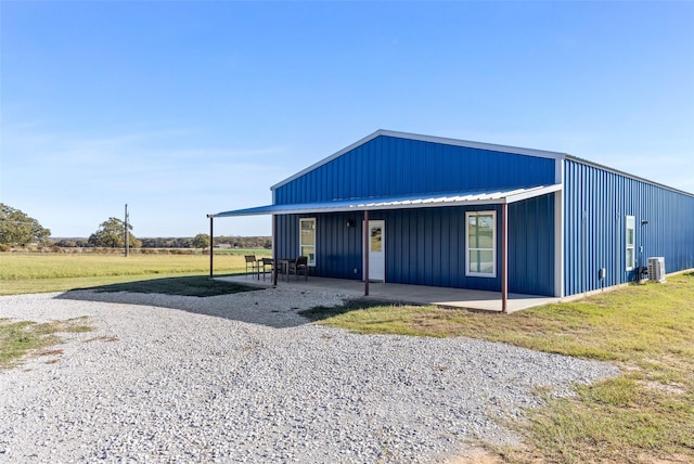 view of front facade featuring metal roof, a patio, board and batten siding, and a front yard