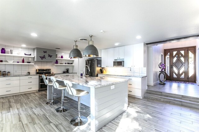 kitchen with decorative backsplash, dishwasher, freestanding refrigerator, open shelves, and a sink