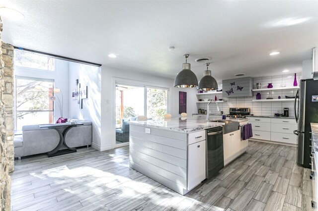 kitchen with beverage cooler, wood finish floors, a sink, visible vents, and an island with sink