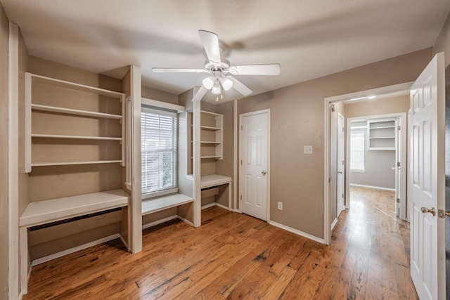 interior space featuring ceiling fan, baseboards, and wood finished floors