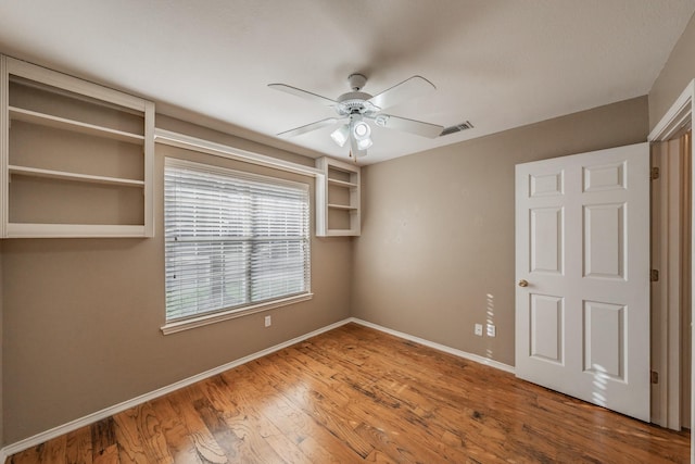 unfurnished bedroom with ceiling fan, wood finished floors, visible vents, and baseboards